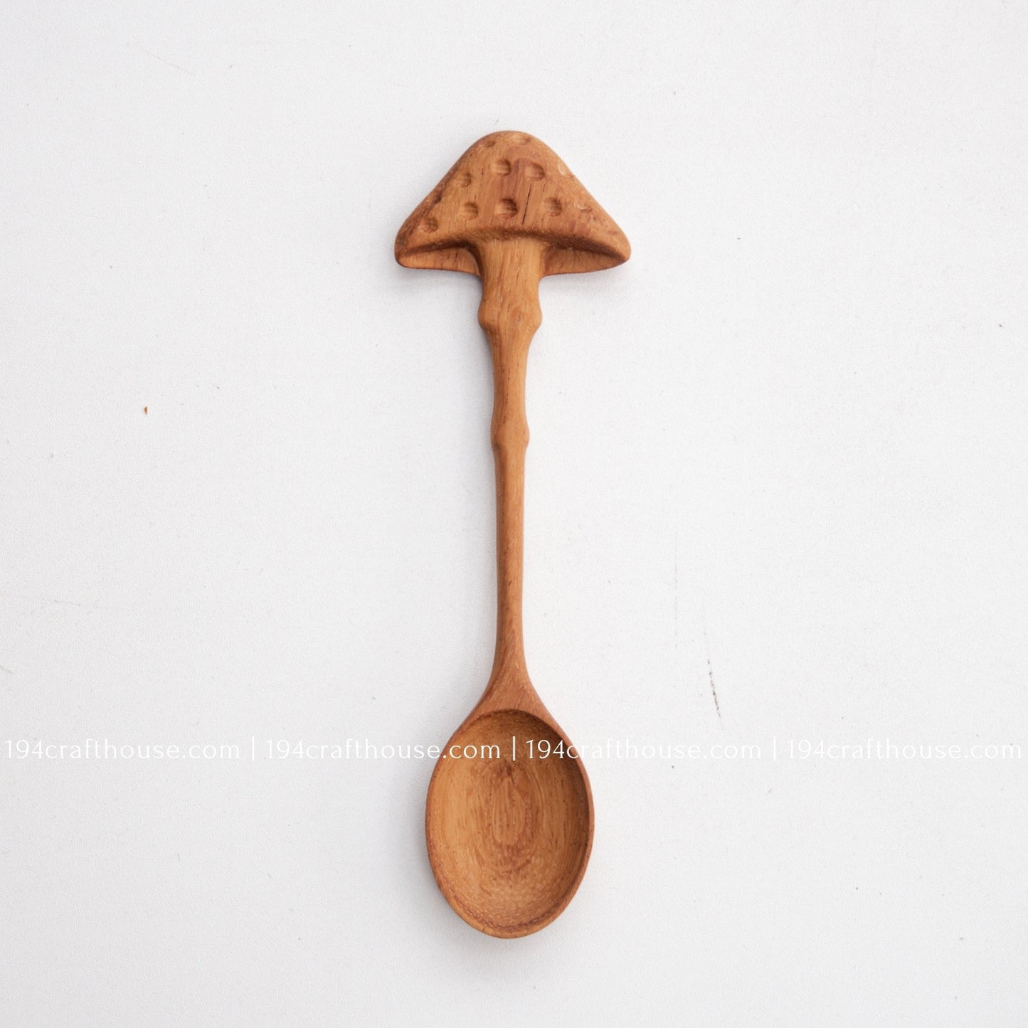 Hand-carved mushroom wooden spoon crafted from doussie wood, featuring a sculpted mushroom cap handle on a white background.