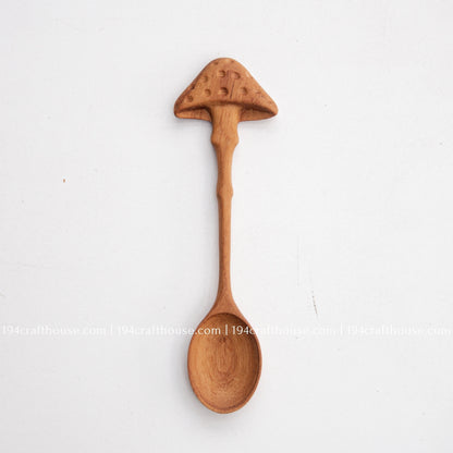 Hand-carved mushroom wooden spoon crafted from doussie wood, featuring a sculpted mushroom cap handle on a white background.