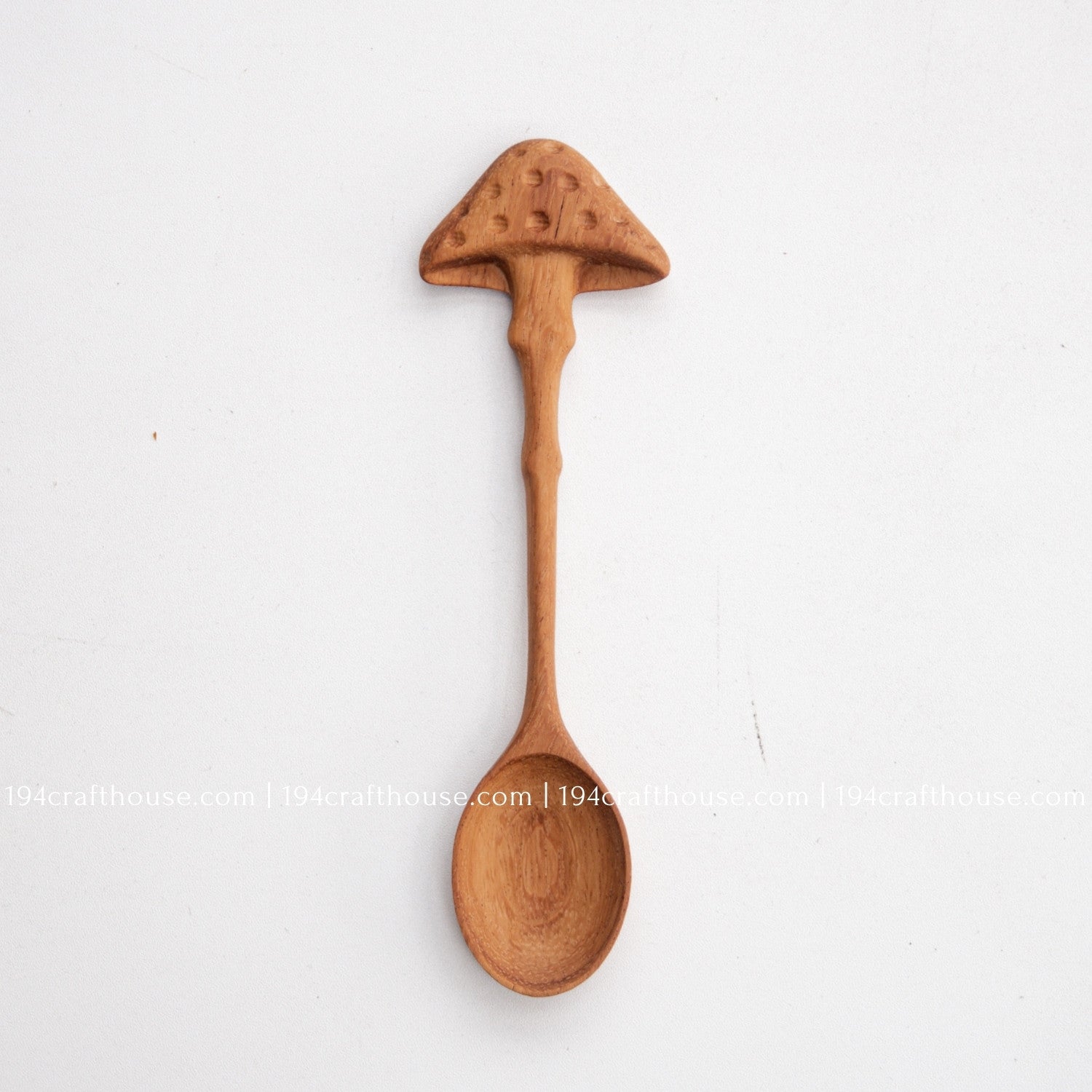 Hand-carved mushroom wooden spoon crafted from doussie wood, featuring a sculpted mushroom cap handle on a white background.