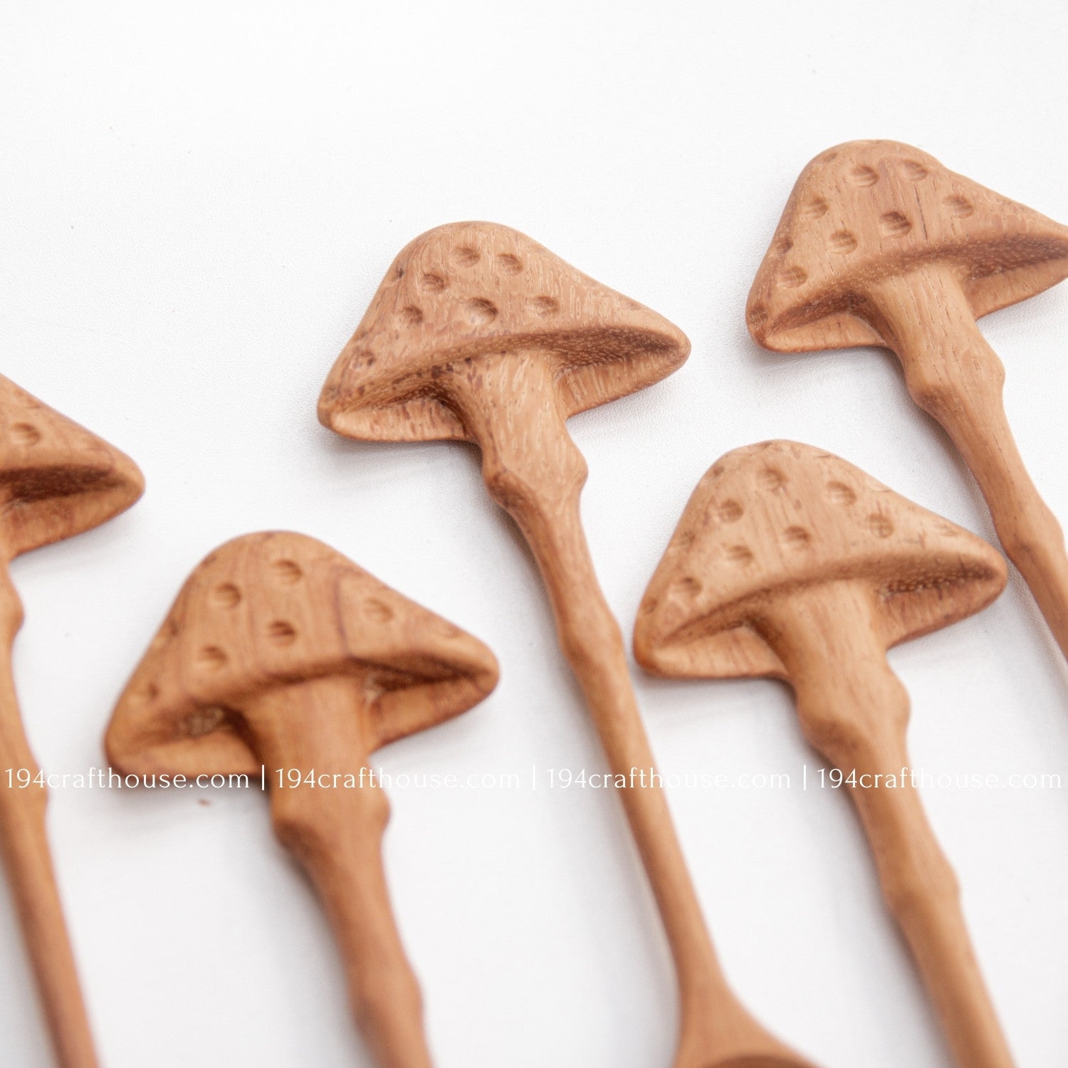 Hand-carved mushroom wooden spoons crafted from doussie wood, featuring a sculpted mushroom cap handle on a white background.