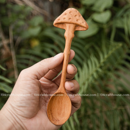 Hand holding a carved mushroom wooden spoon with natural woodland background