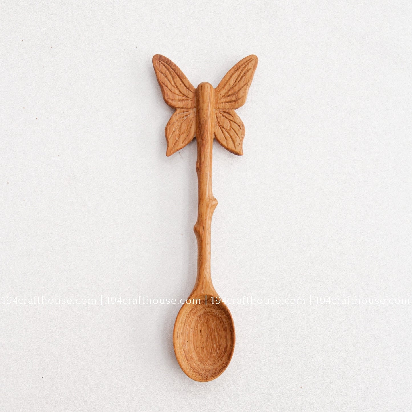 Hand-carved Butterfly wooden spoon crafted from doussie wood, featuring a sculpted butterfly handle on a white background.