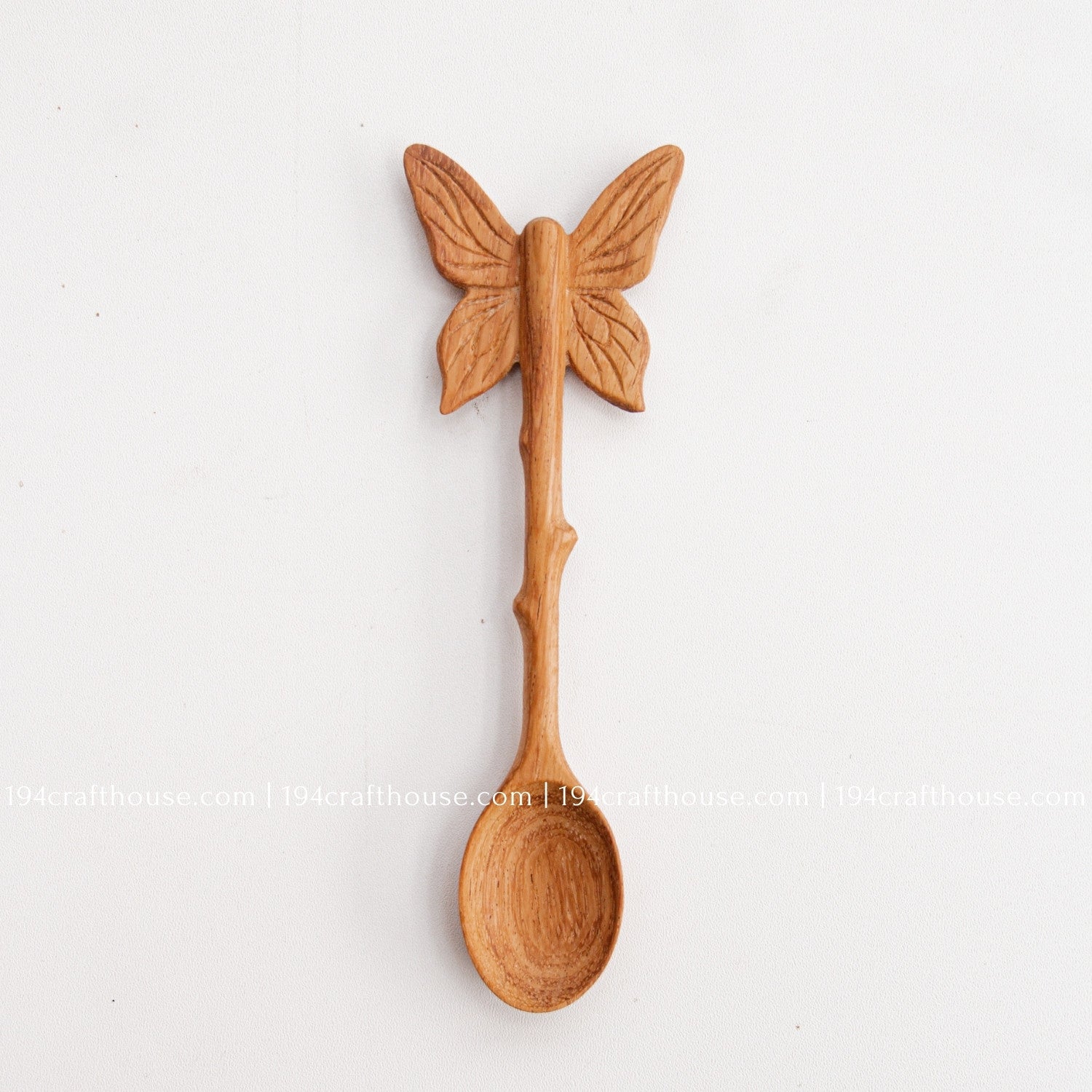 Hand-carved Butterfly wooden spoon crafted from doussie wood, featuring a sculpted butterfly handle on a white background.
