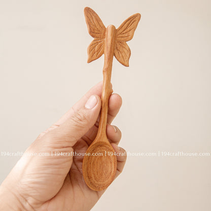 Hand-carved Butterfly wooden spoon crafted from doussie wood, featuring a sculpted butterfly handle hod by on a white background.and 