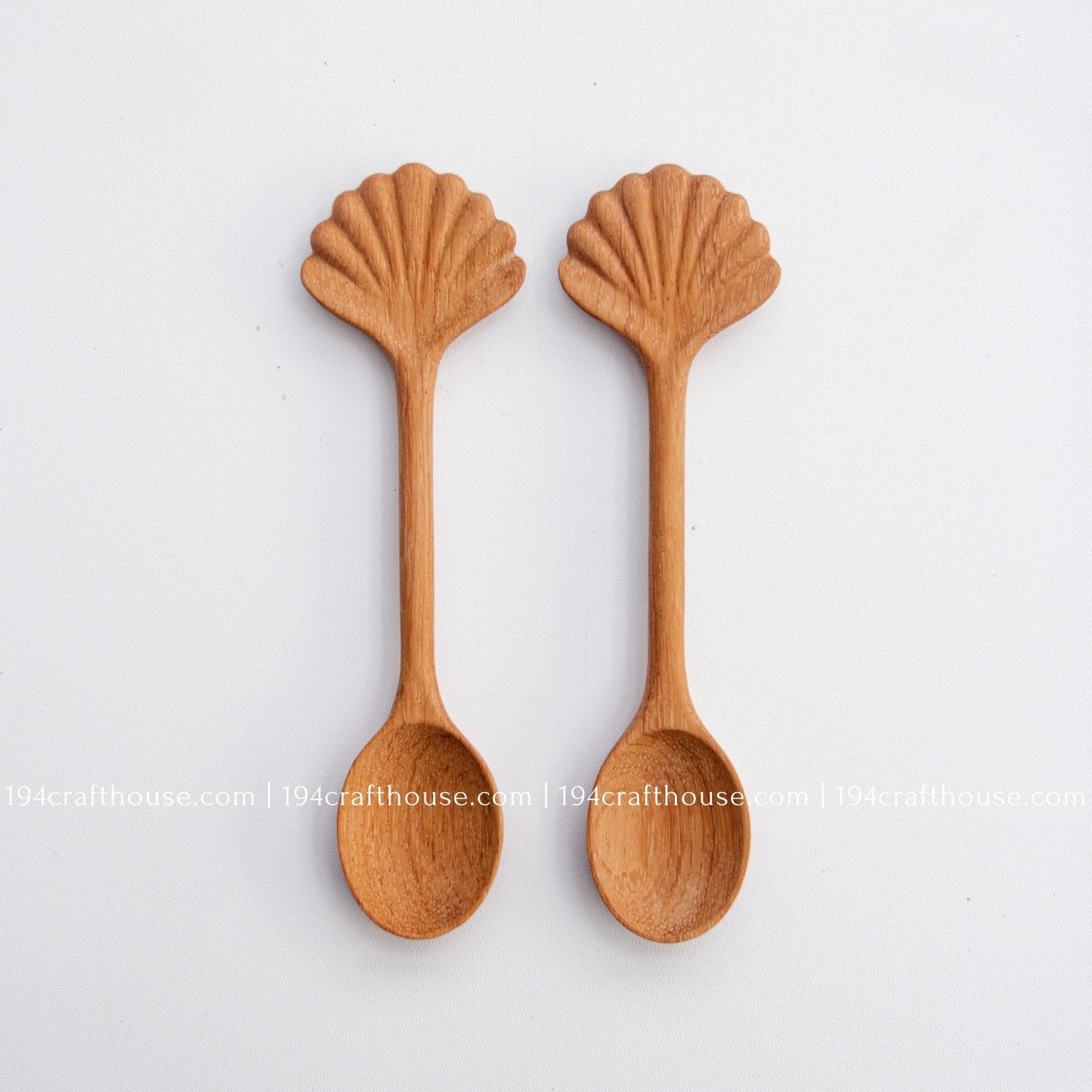 Hand-carved seashell wooden spoon crafted from doussie wood, featuring a sculpted mushroom cap handle on a white background.