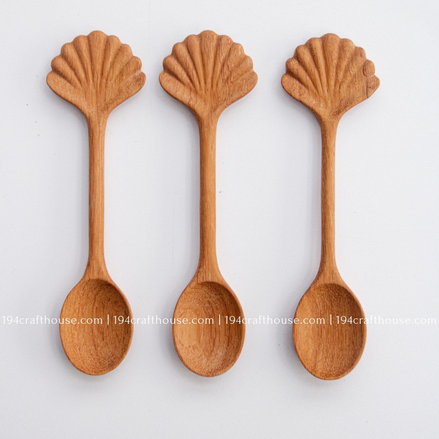 Hand-carved seashell wooden spoon crafted from doussie wood, featuring a sculpted mushroom cap handle on a white background.