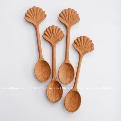 Hand-carved seashell wooden spoon crafted from doussie wood, featuring a sculpted mushroom cap handle on a white background.