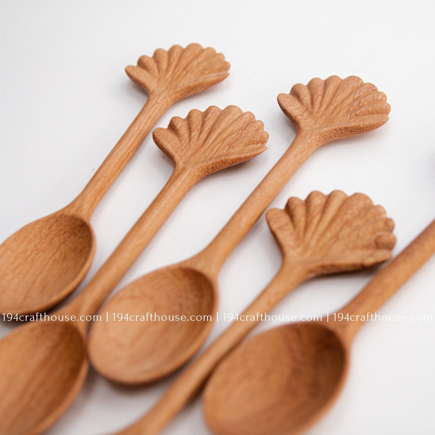 Hand-carved seashell wooden spoon crafted from doussie wood, featuring a sculpted mushroom cap handle on a white background.
