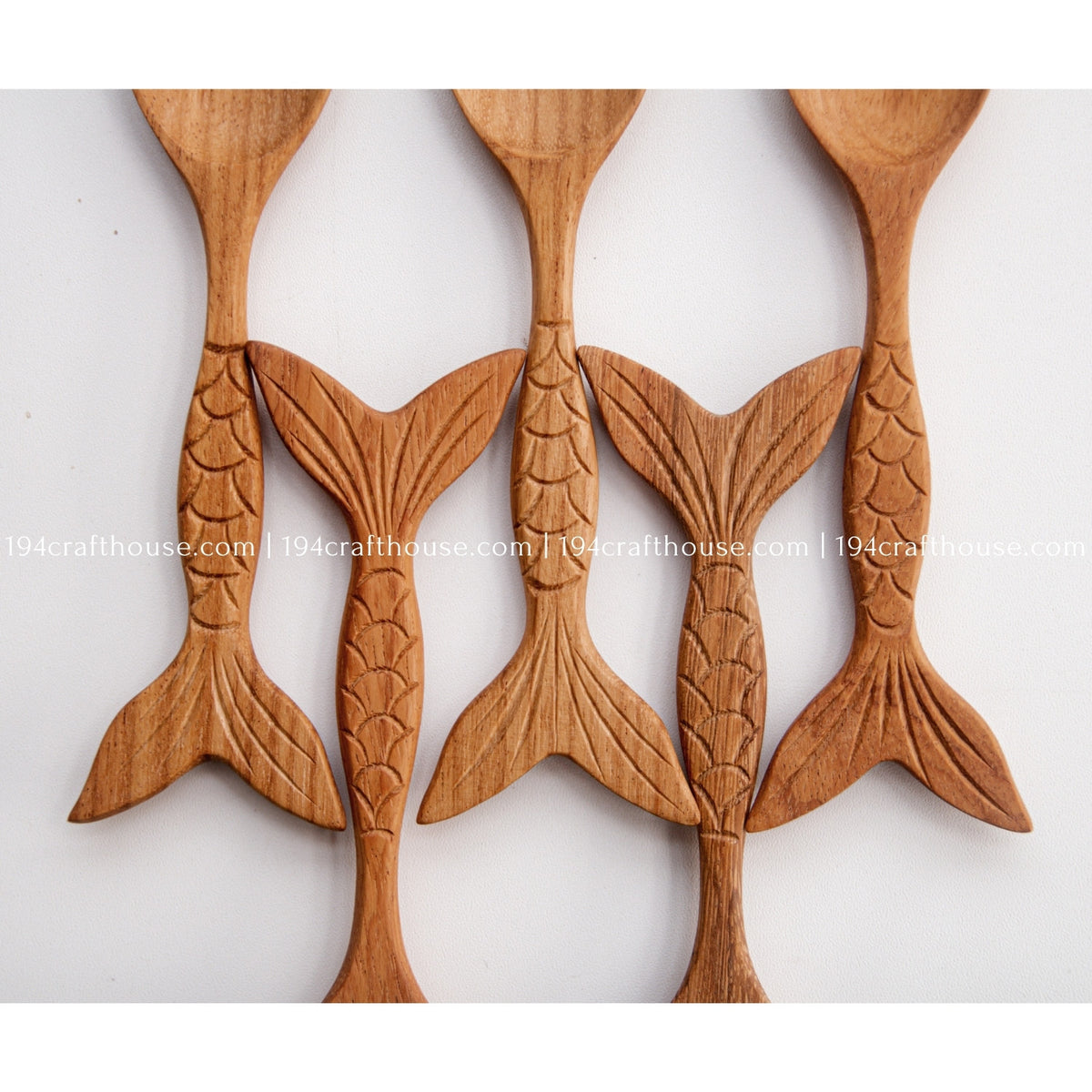 Close view of multiple fish-tail handles showing carved scale patterns and natural Doussie wood grain.