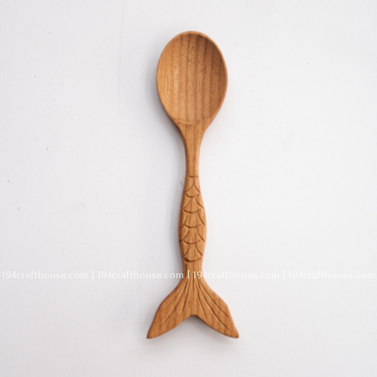 Single fish-tail handle Doussie wood spoon shown full length on a clean pale background.