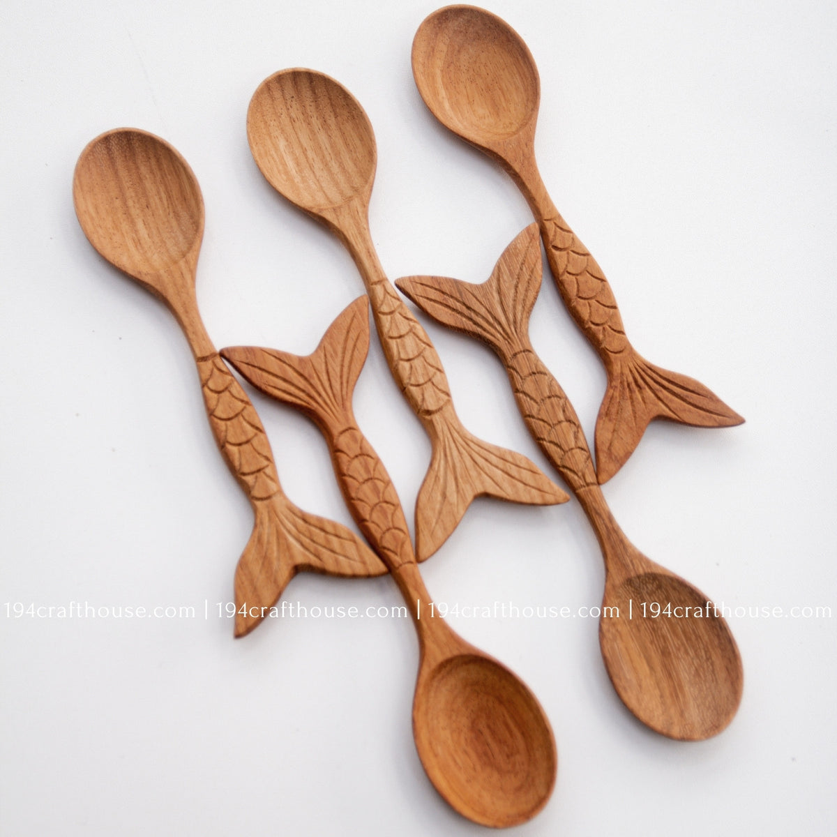 Four Doussie wood spoons in an alternating arrangement, highlighting their fish-tail ends and natural grain.