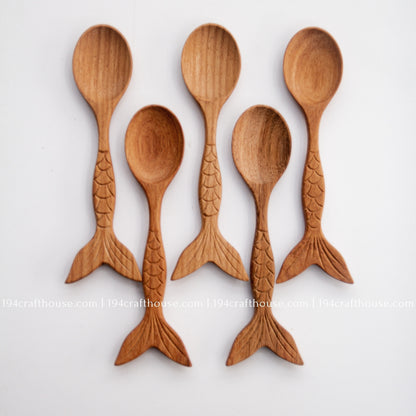 Five handcrafted Doussie wood spoons arranged together, showing oval bowls and fish-tail handles.