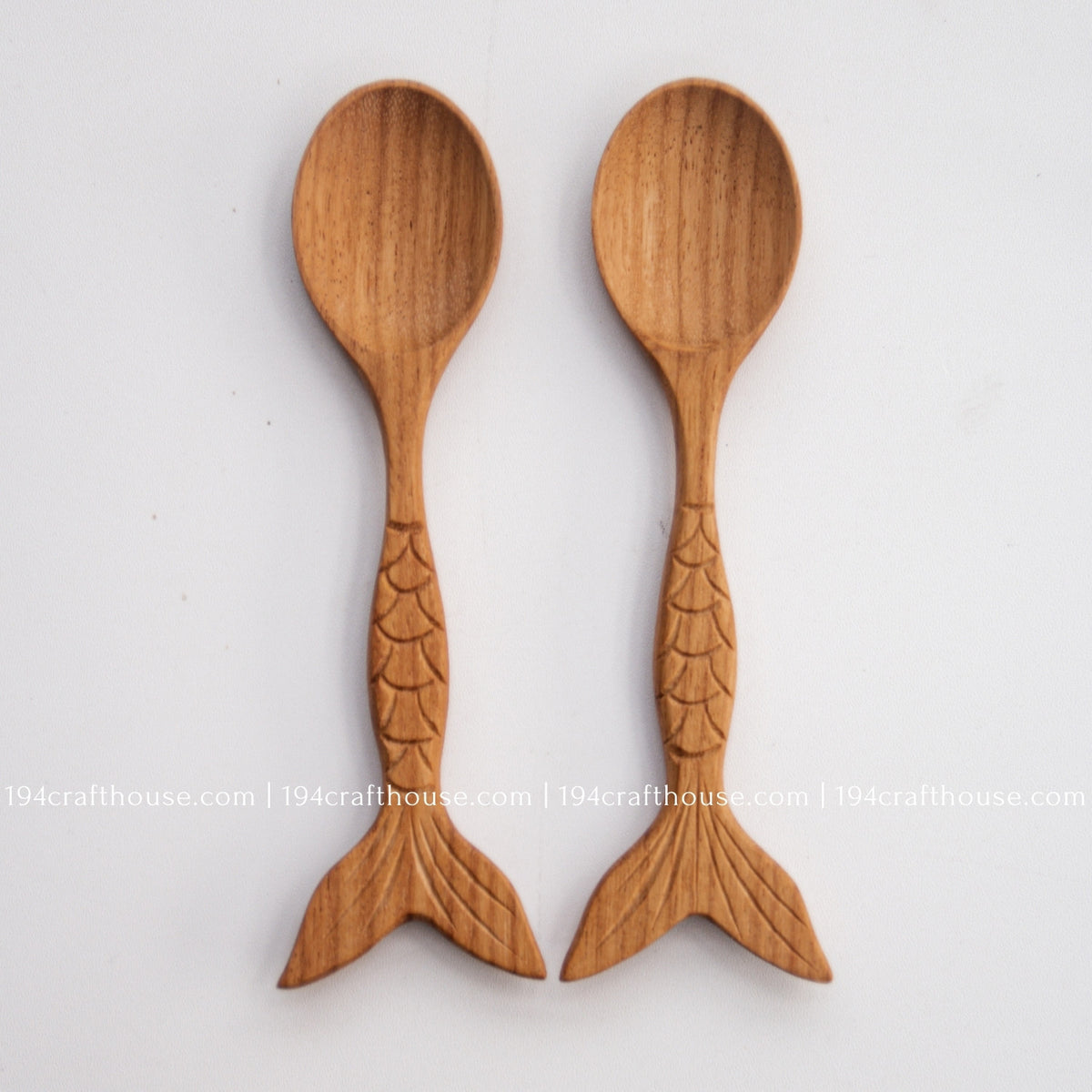 Two fish-tail handle Doussie wood spoons side by side, showing natural grain and carving variation.