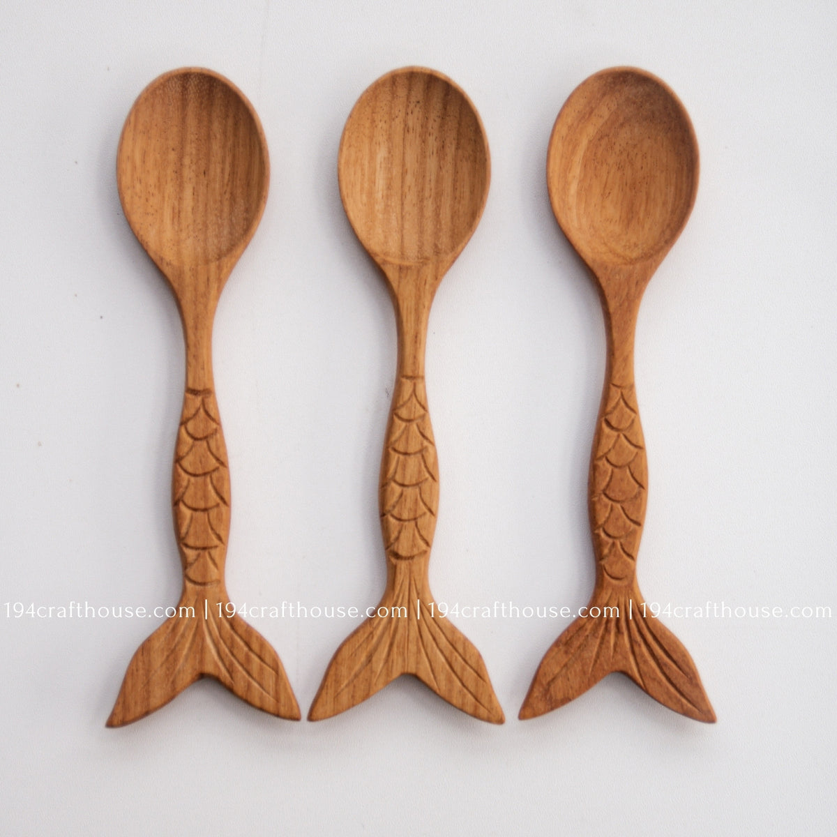 Three Doussie wood spoons arranged together to show differences in wood tone, grain and hand carving.