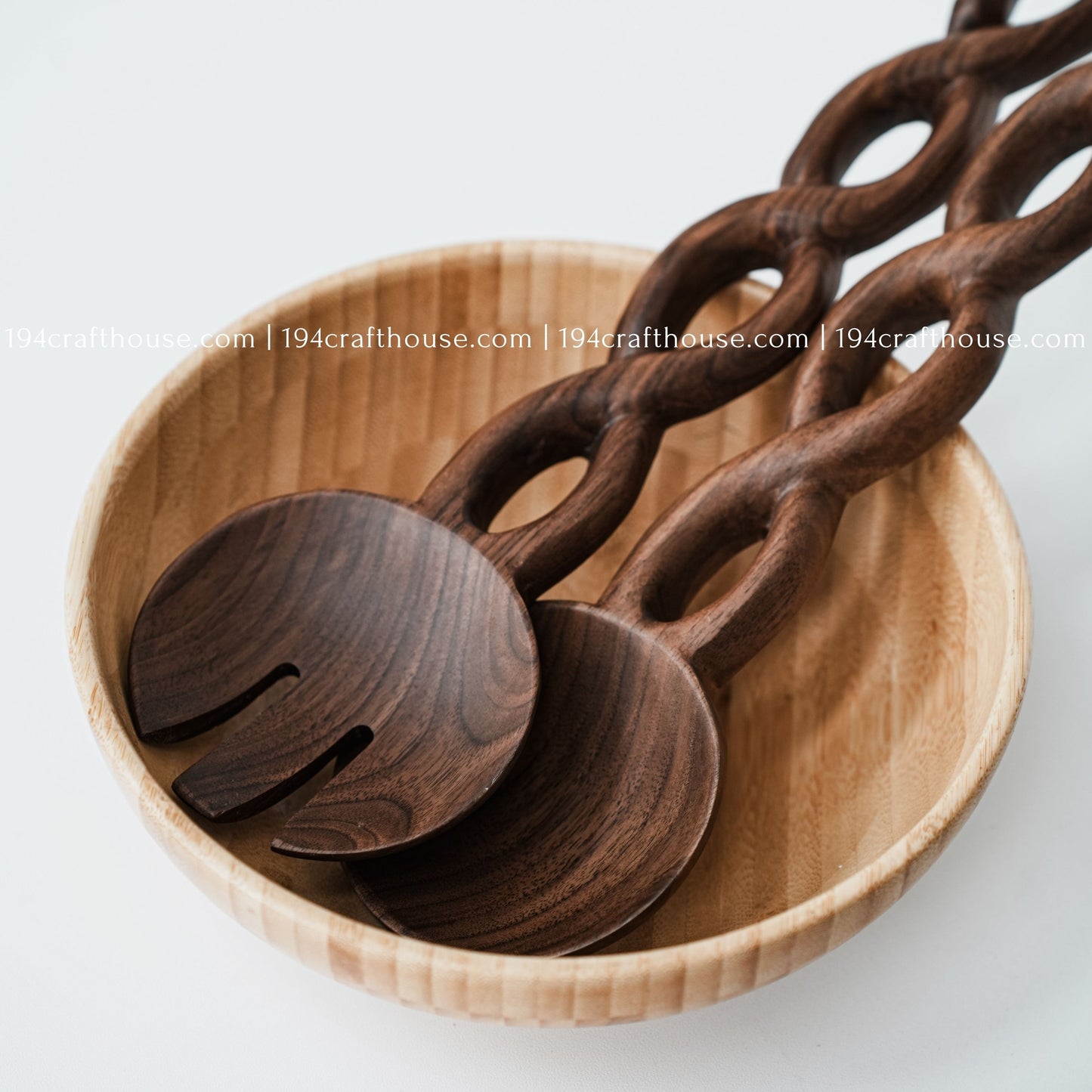 Handcrafted chain-handle wooden salad servers displayed inside a natural wooden serving bowl