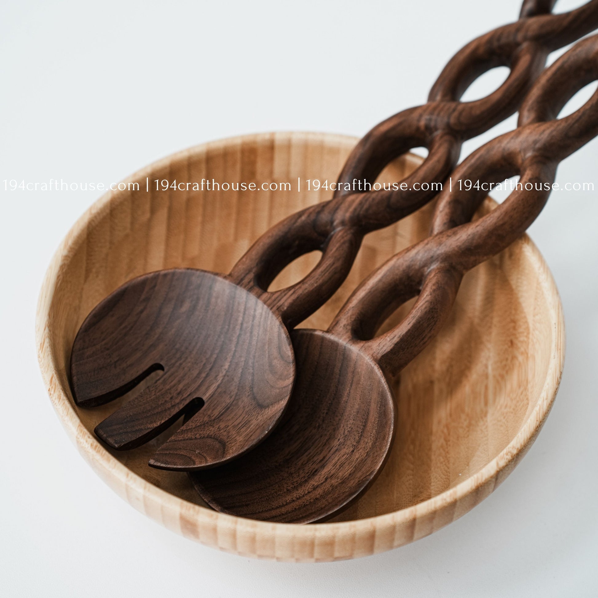 Handcrafted chain-handle wooden salad servers displayed inside a natural wooden serving bowl