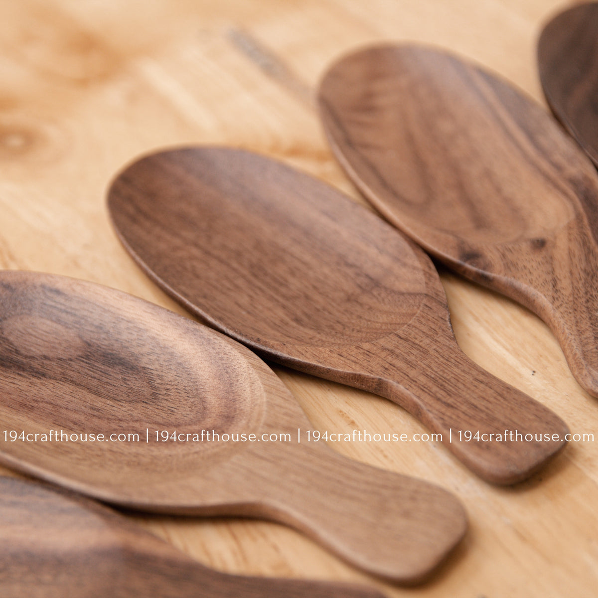 Close view of walnut wood tea scoop bowls showing smooth carving and distinctive natural grain.