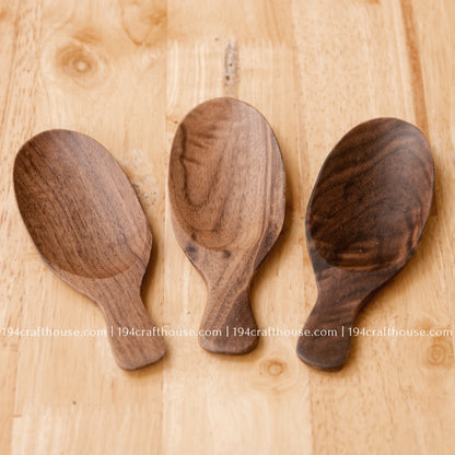 Three walnut wood tea scoops together, showing natural variation in grain, tone and bowl shape.