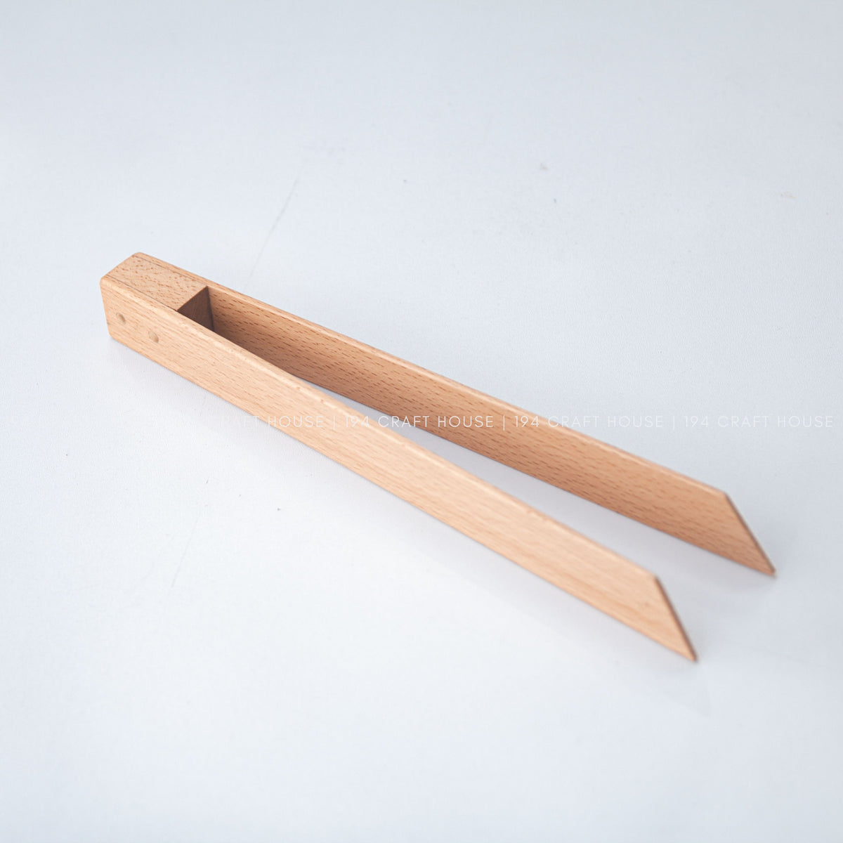 Beech wood salad tongs angled diagonally with their two arms open.