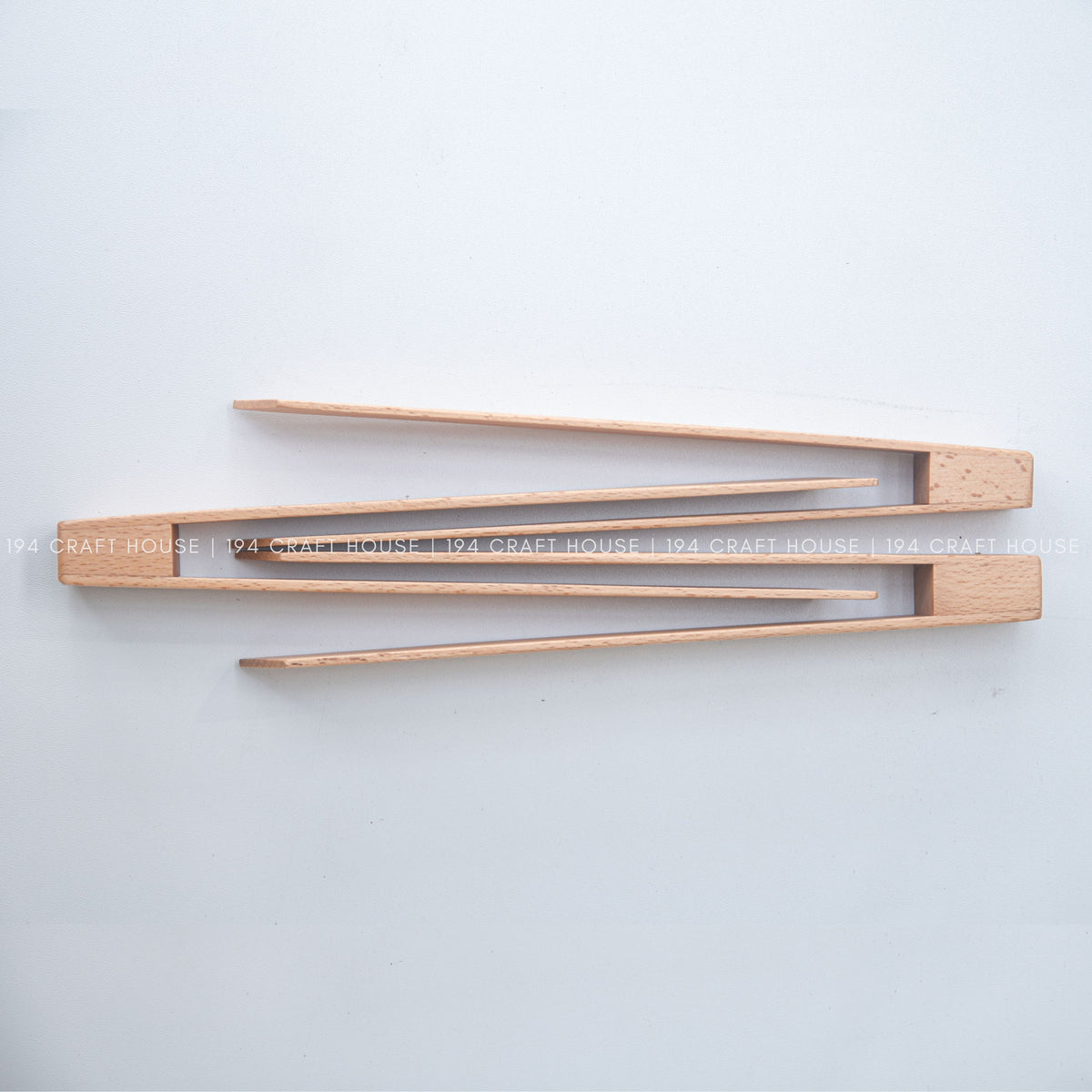 Top view of the open tongs showing their long arms and connecting block.