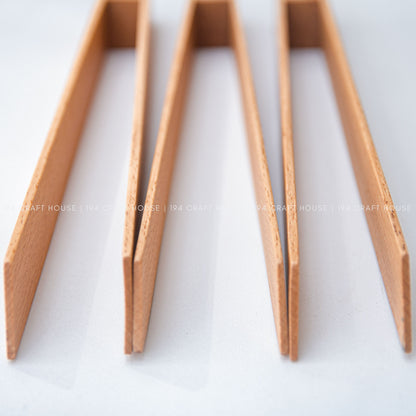Close-up view of the narrow wooden ends and grain on the salad tongs.