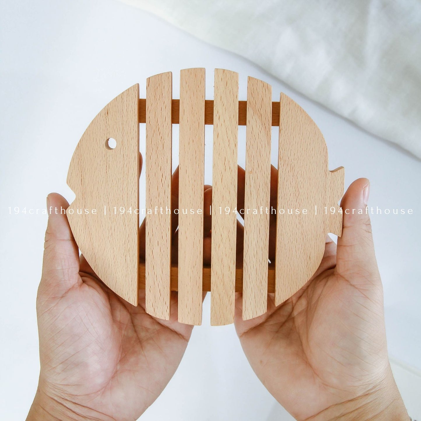 Wooden fish-shaped trivet held in hand to show its size and handcrafted design