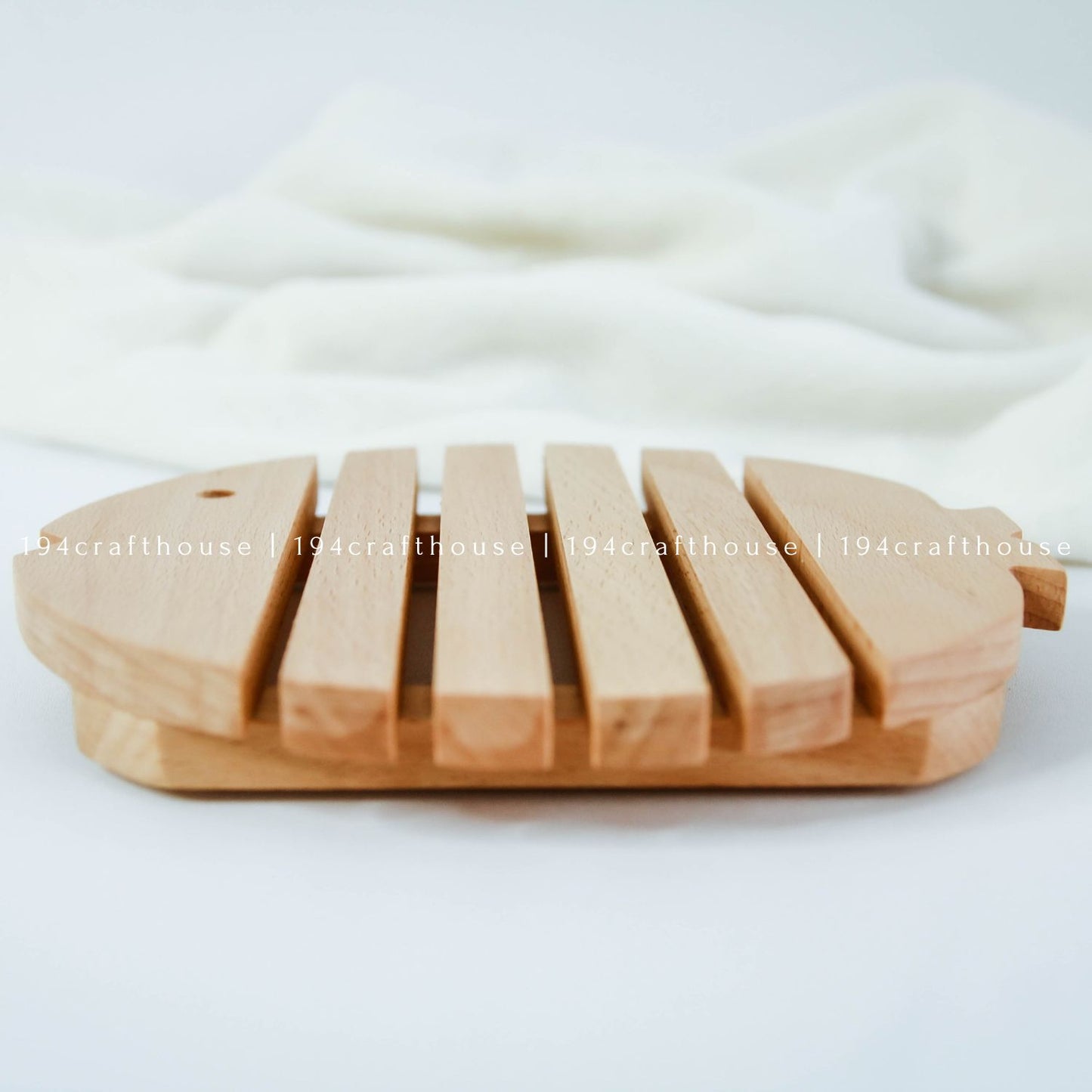 Side view of a handcrafted wooden fish trivet showing its raised structure and thickness