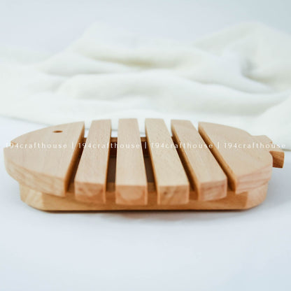 Side view of a handcrafted wooden fish trivet showing its raised structure and thickness