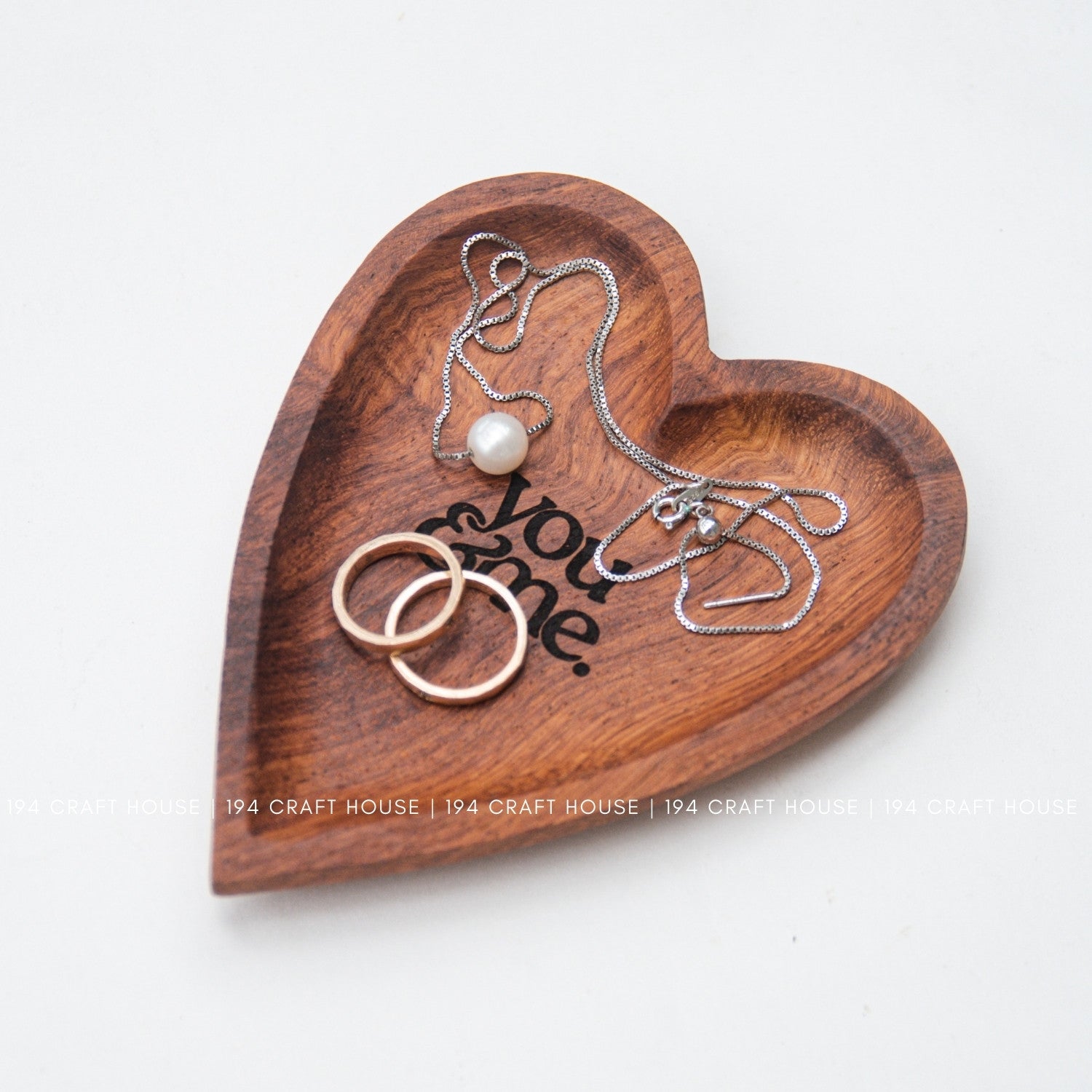 Heart-shaped wooden tray with jewelry on a white background
