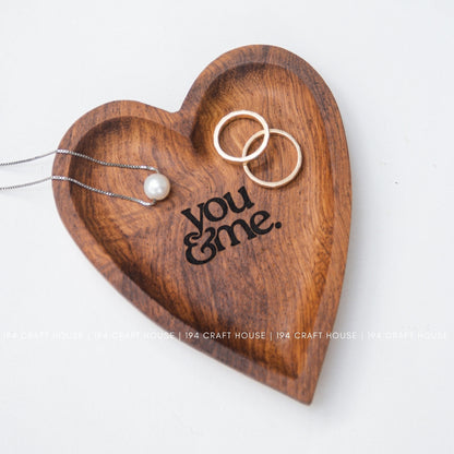 Wooden heart-shaped jewelry holder with 'you & me' engraving on a white background