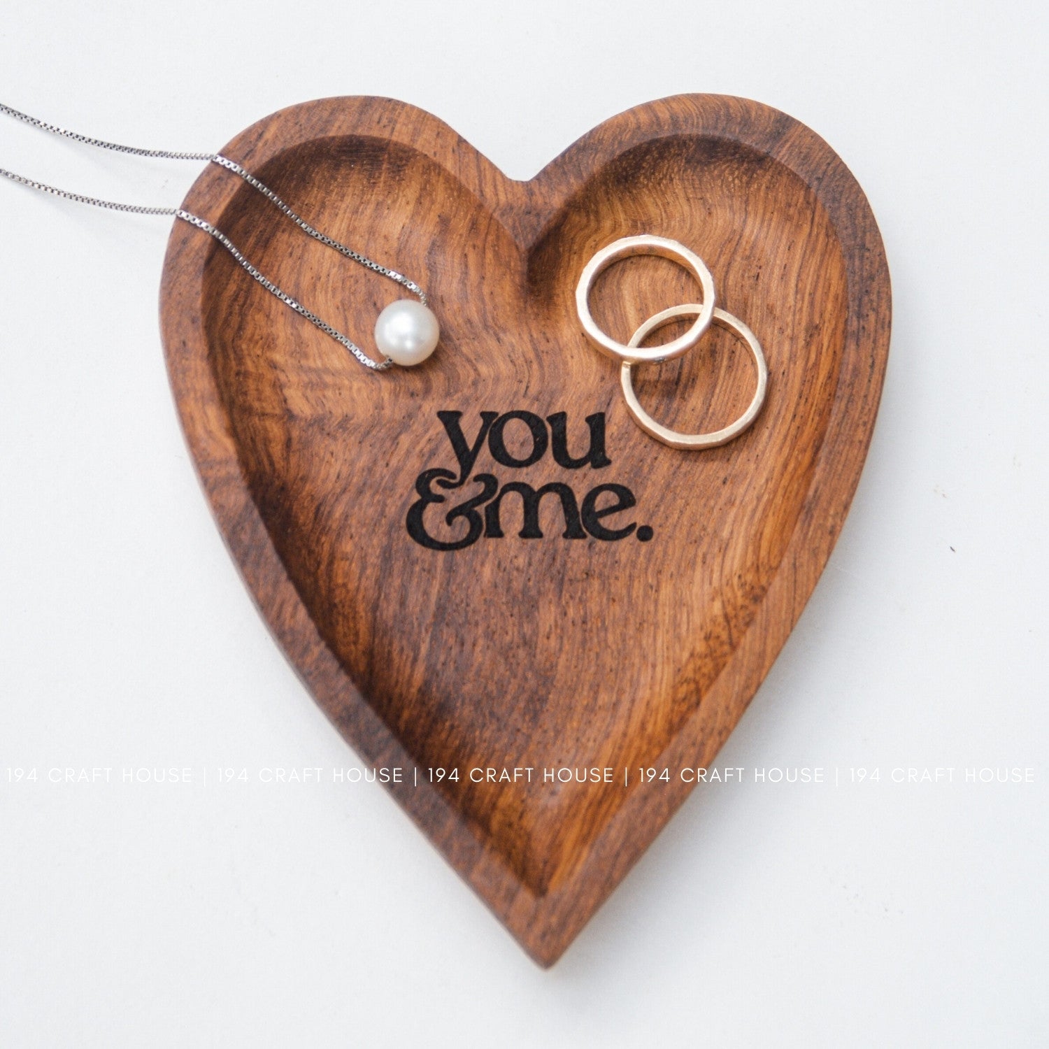 Wooden heart-shaped tray with 'you & me' engraving, jewelry on a white background