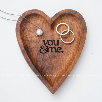 Wooden heart-shaped tray with 'you & me' engraving, jewelry on a white background