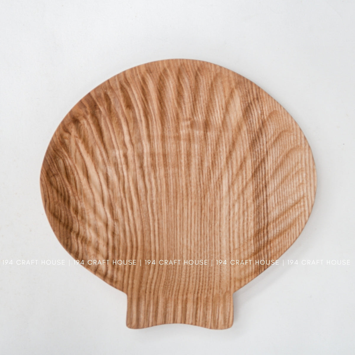Close view of the shell-inspired tray showing its reddish-brown ash grain and projecting tab.