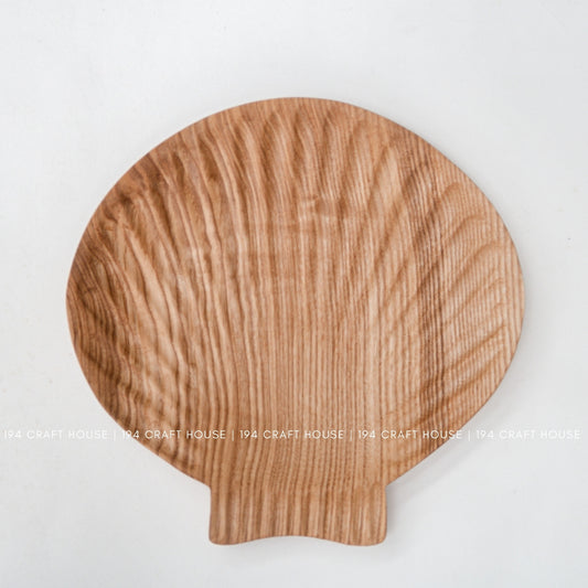 Close view of the shell-inspired tray showing its reddish-brown ash grain and projecting tab.