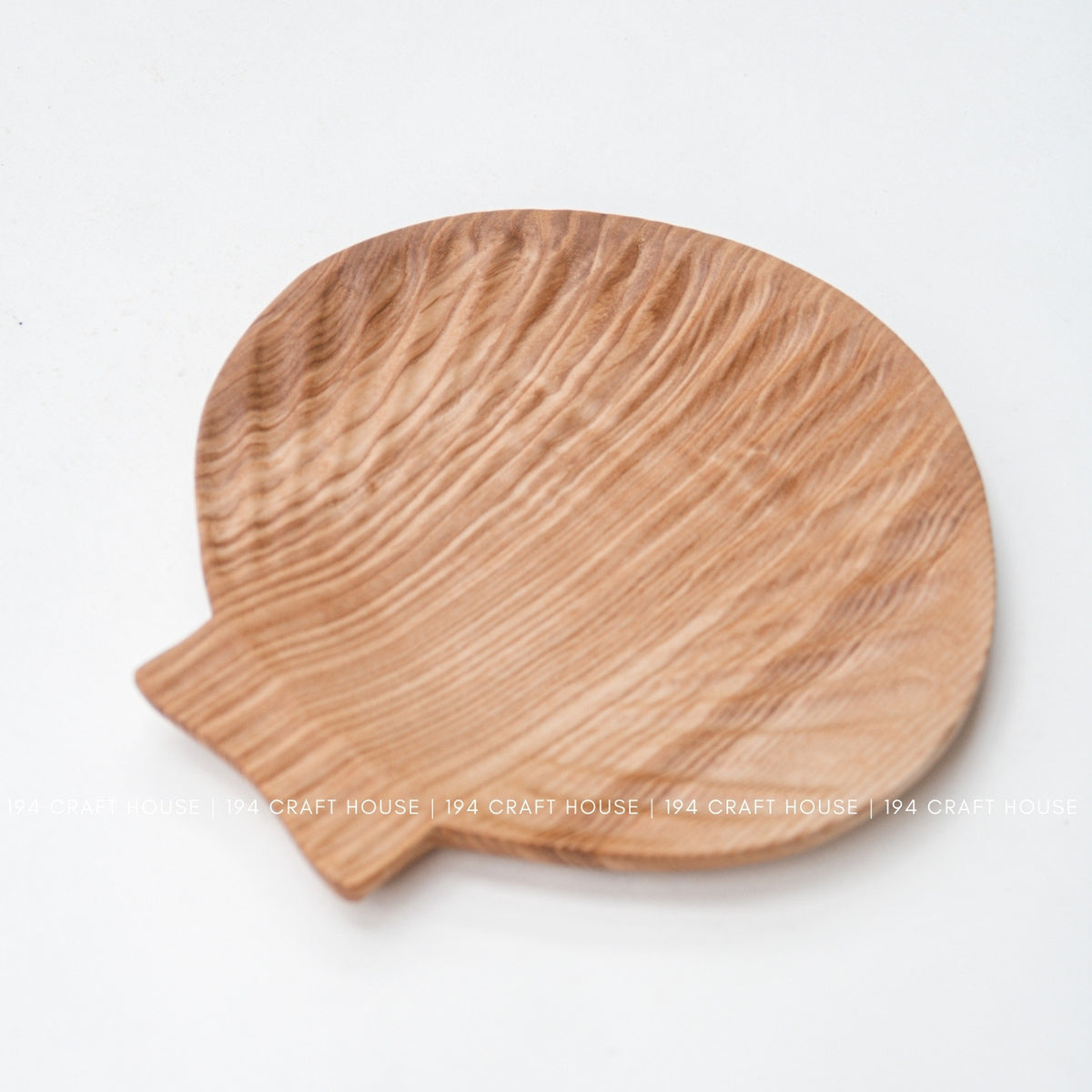 Ash wood tray shown from above on a white background, with rounded shell-inspired shape and projecting tab.