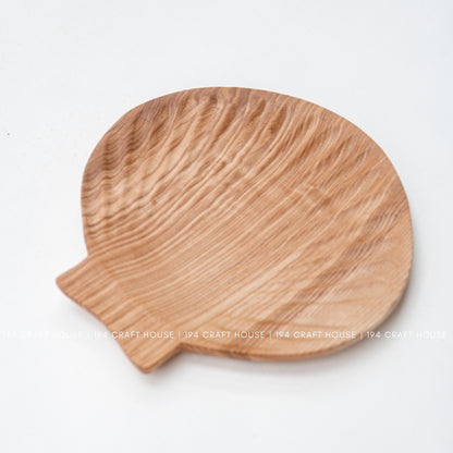 Ash wood tray shown from above on a white background, with rounded shell-inspired shape and projecting tab.