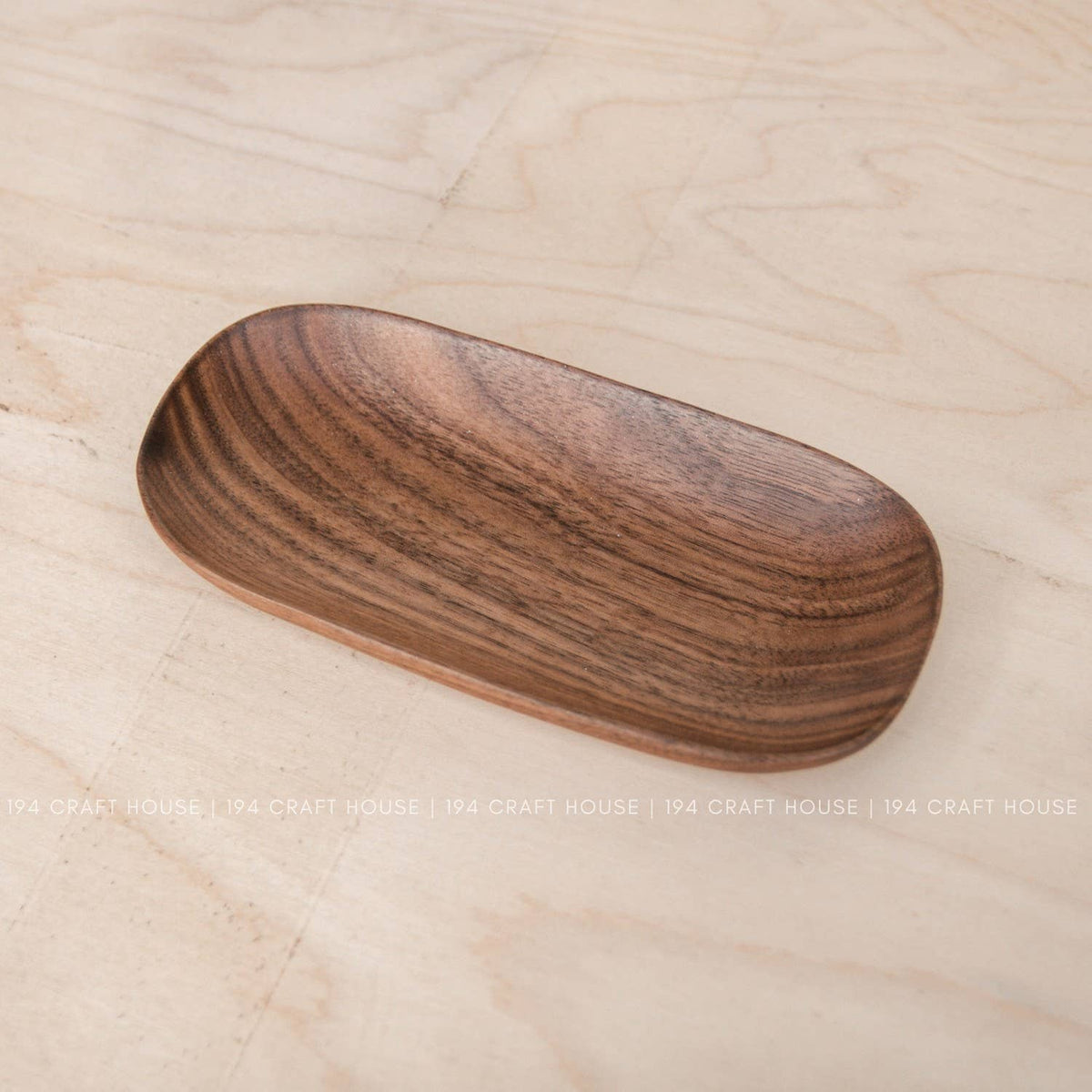 Wooden oval tray with shallow center and rounded ends in warm brown wood on a light surface