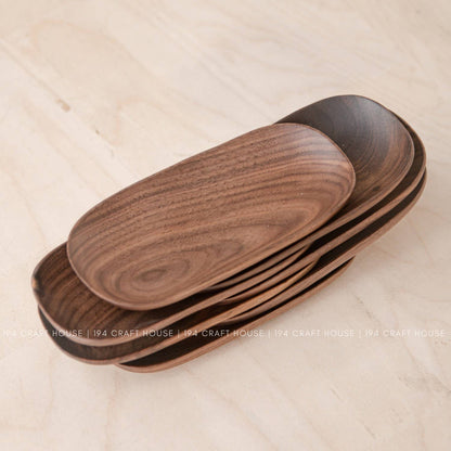 Nested stack of wooden oval trays in warm brown seen from above on a light wood surface