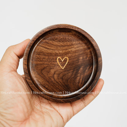 Handmade walnut jewelry dish held in hand with gold heart engraving and a smooth rounded rim