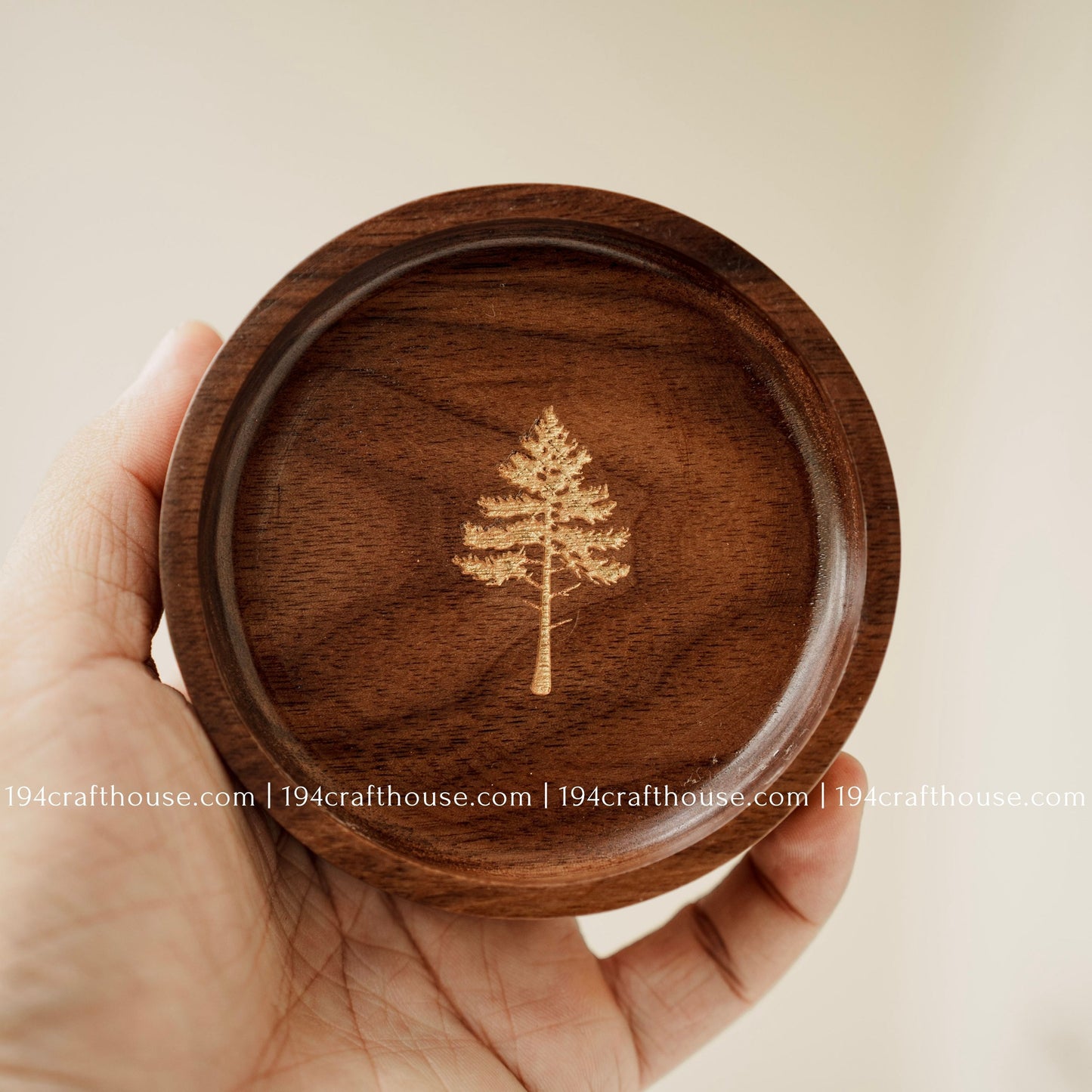 Handmade walnut wood jewelry dish held in hand, featuring a detailed pine tree engraving and natural walnut grain