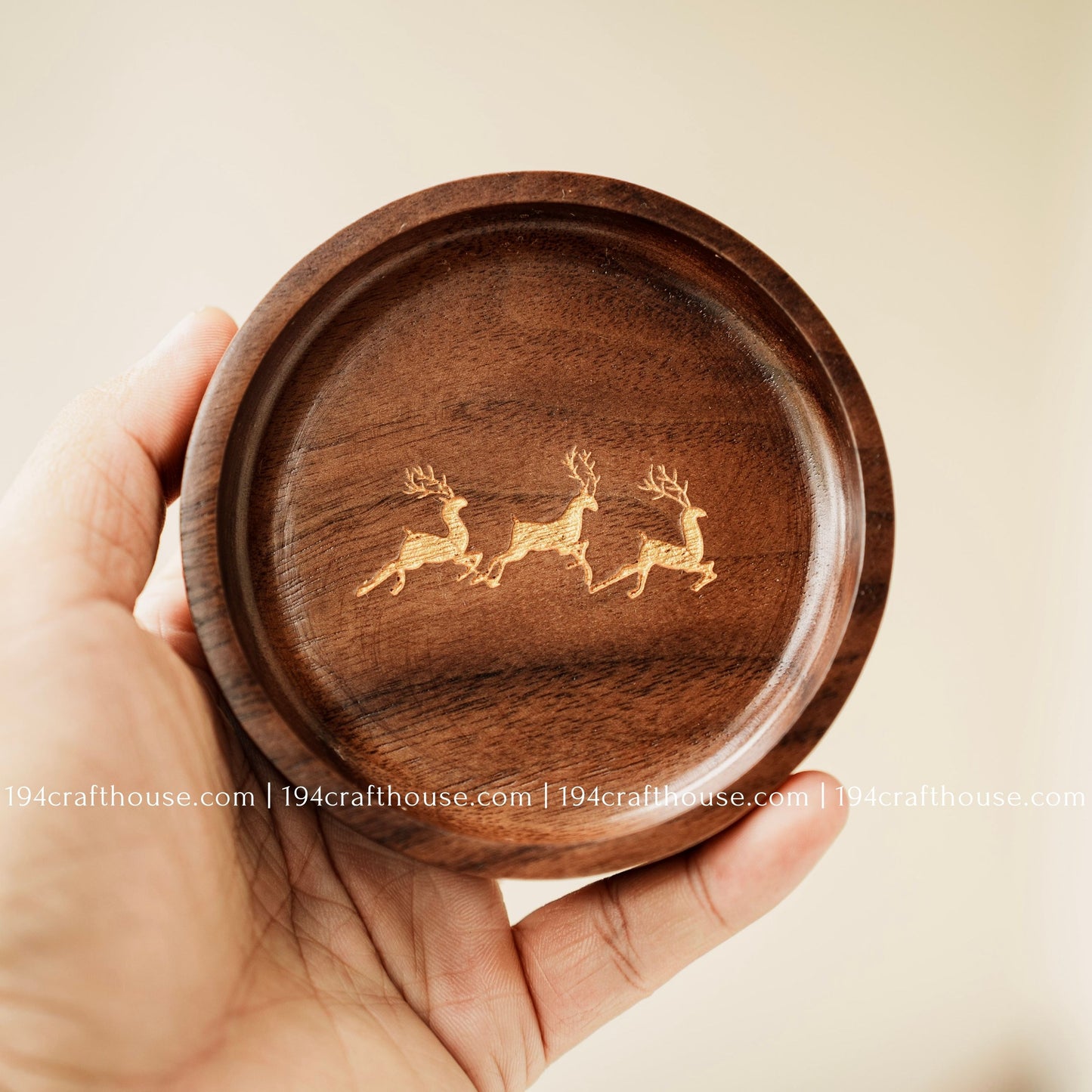 Walnut wood jewelry dish held in hand to show its size, carved shape, deer engraving, and natural wood grain