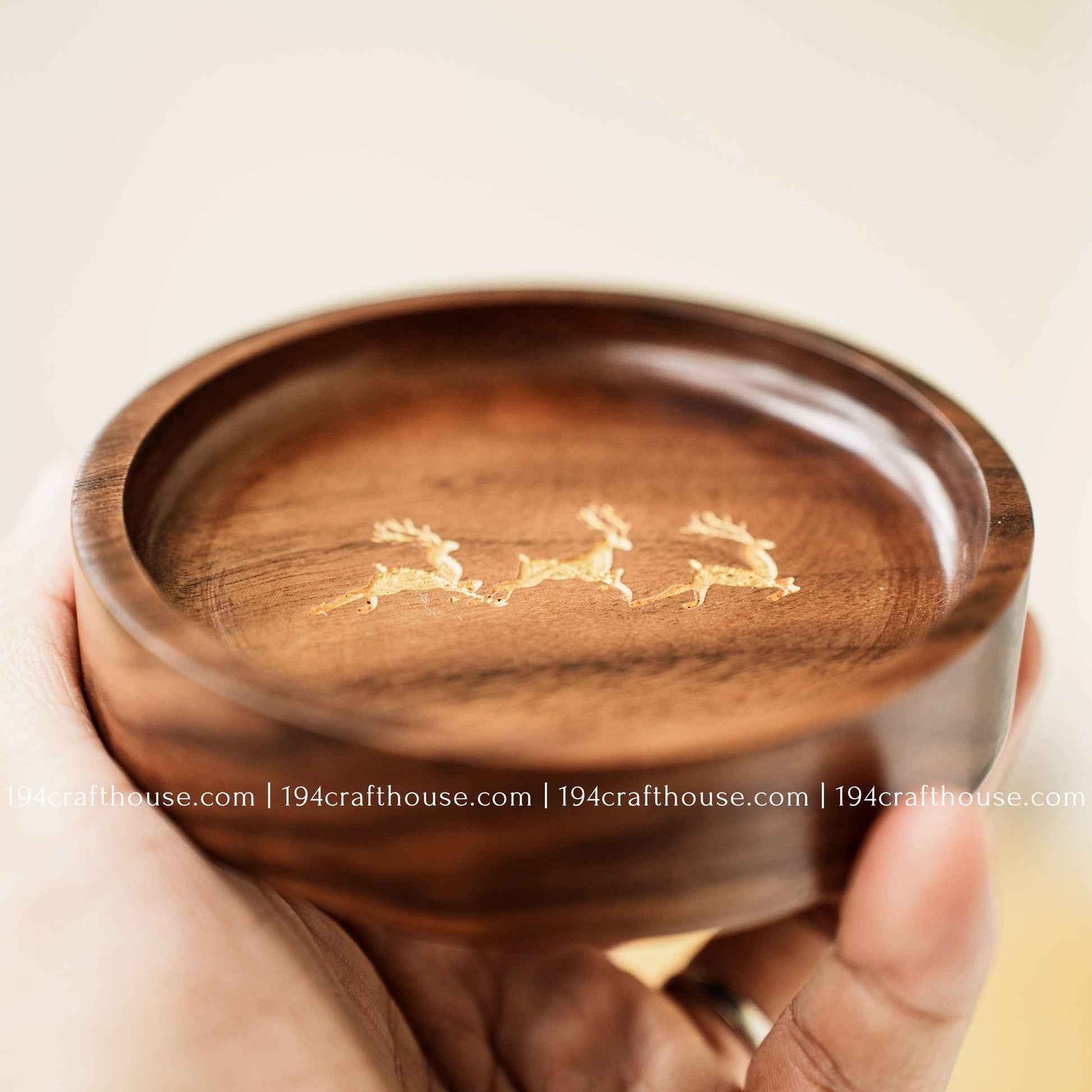 Close-up of a walnut wood ring dish with engraved deer trio design and smooth polished interior