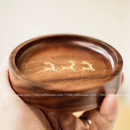 Close-up of a walnut wood ring dish with engraved deer trio design and smooth polished interior
