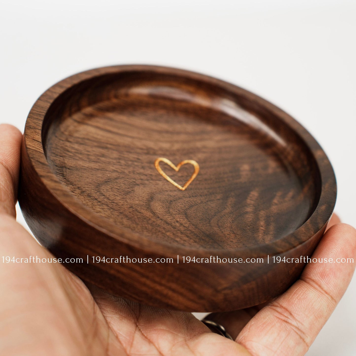 Close-up of a handcrafted walnut wood ring tray featuring a gold heart engraving and natural walnut wood grain