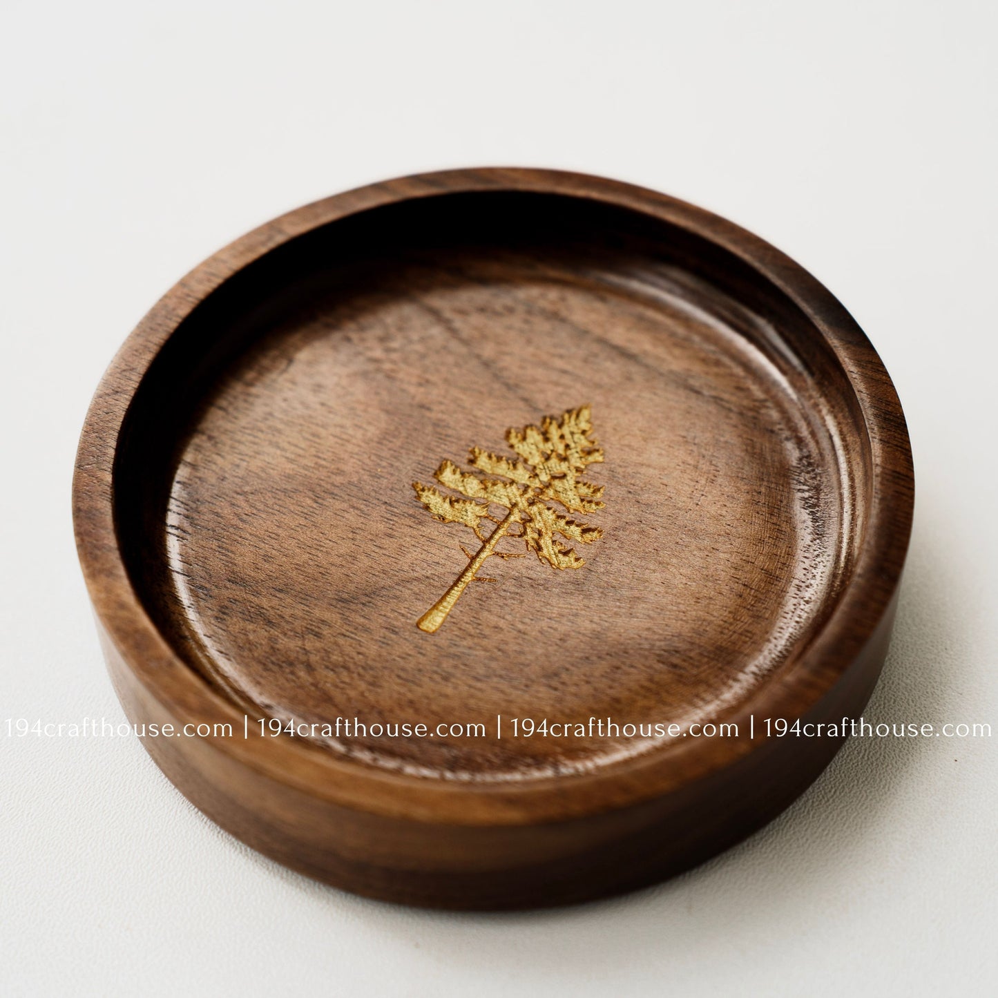 Close-up of a walnut wood ring tray with pine tree engraving, handcrafted finish, and natural dark wood grain