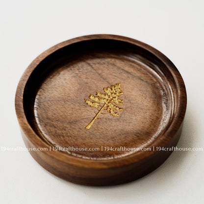 Close-up of a walnut wood ring tray with pine tree engraving, handcrafted finish, and natural dark wood grain