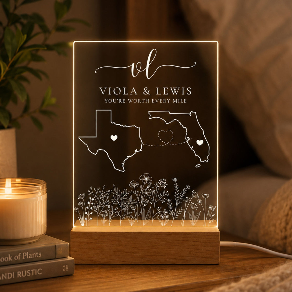 Long distance relationship acrylic night light featuring wildflower garden engraving, custom Texas and Florida state outlines, monogram initials, and warm LED wooden base on a bedside table.