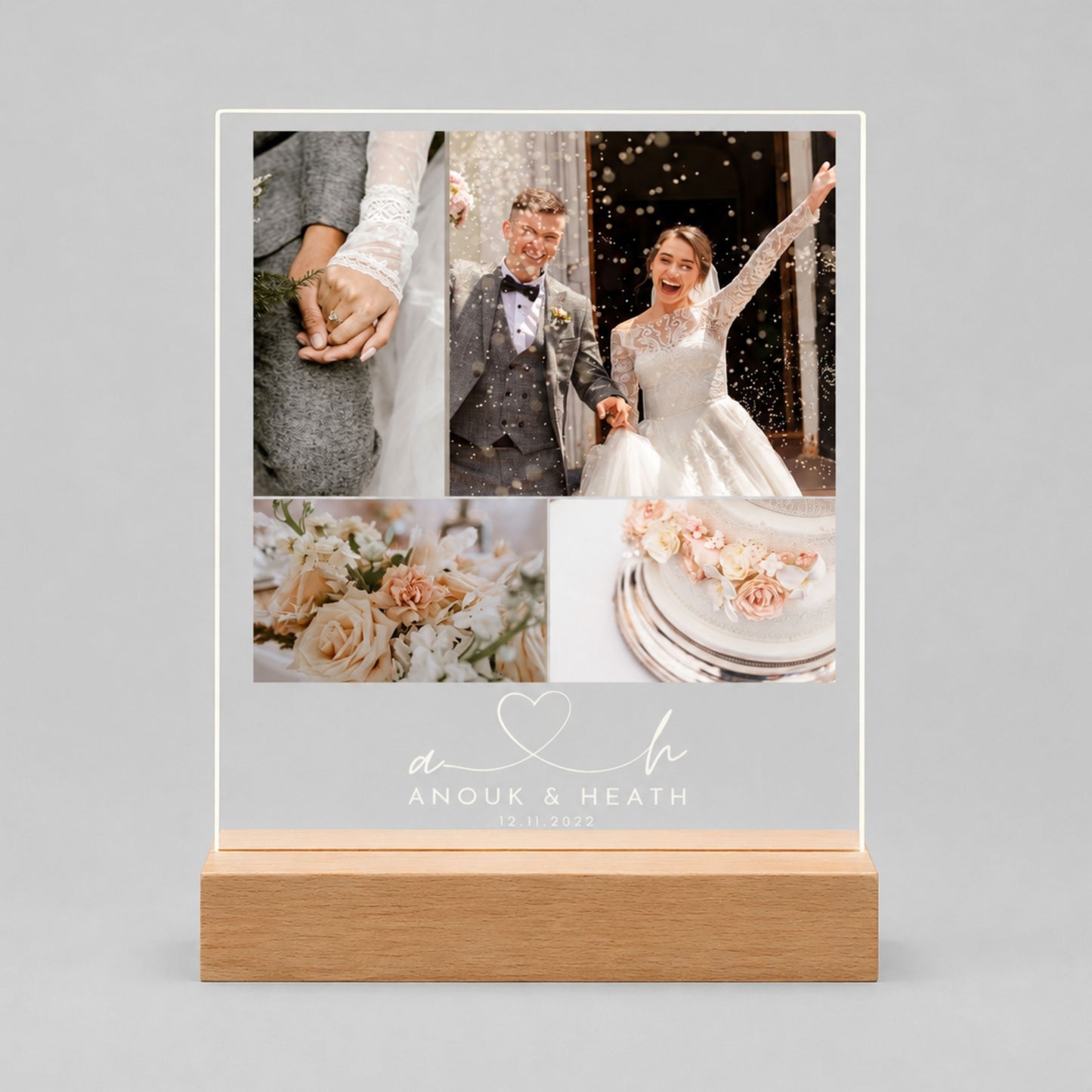 Studio front view of unlit clear acrylic plaque printed with a 4-photo wedding collage, monogram initials heart line, couple names, and date on a natural beech wood base.