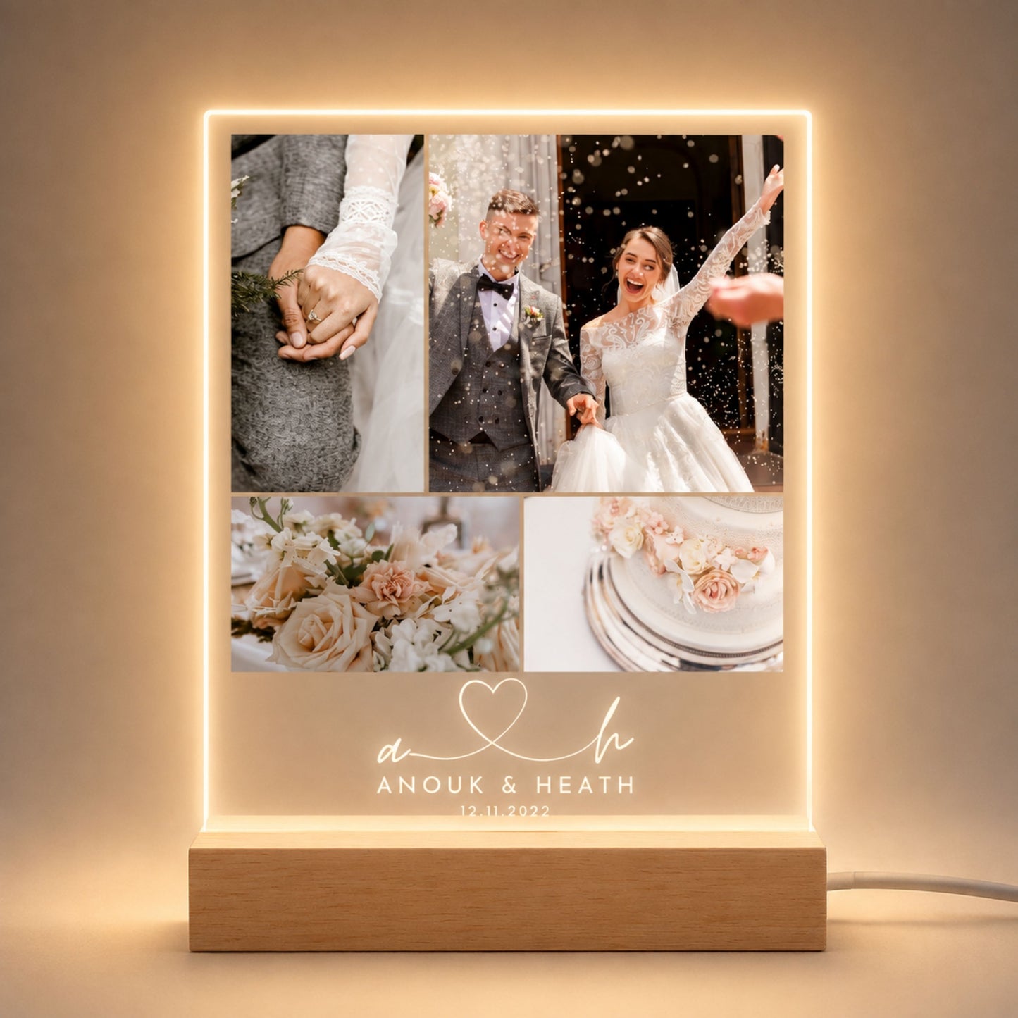 Studio front view of illuminated four-picture wedding collage acrylic plaque with script monogram initials glowing warm white on a natural wooden LED stand.
