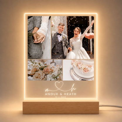 Studio front view of illuminated four-picture wedding collage acrylic plaque with script monogram initials glowing warm white on a natural wooden LED stand.